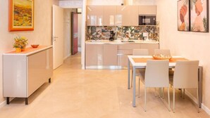 A modern kitchen with white cabinets, a dining area with a table and chairs, and artwork on the walls. - Blue Lake Residence (Bardolino)