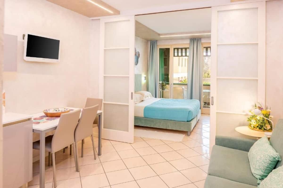 A room with a bed, a desk, a chair, and a sofa.