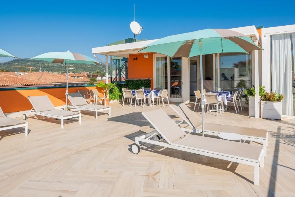 Eine Dachterrasse mit Liegestühlen, Sonnenschirmen und Blick auf die umliegende Landschaft.