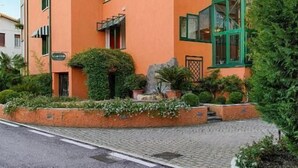 A multi-story hotel with a prominent orange facade, large windows, and a rooftop terrace. - Blue Lake Residence (Bardolino)