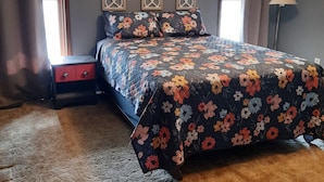 Ein Schlafzimmer mit Bett, Nachttisch, Lampe und dekorativen Wandverkleidungen.