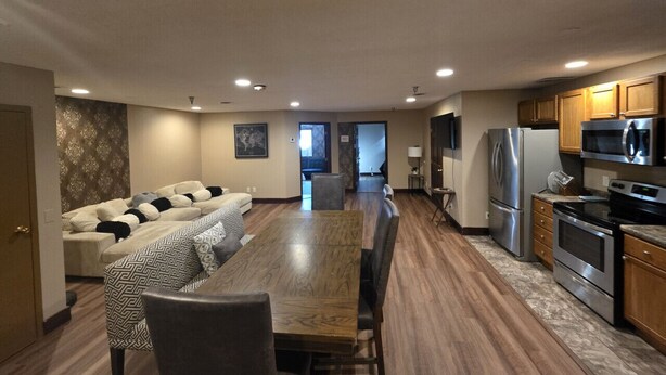 A modern kitchen with stainless steel appliances, a dining area with a wooden table, and a living room with a sofa and patterned cushions. - Big space on Deadwood`s Main Street! (Deadwood)