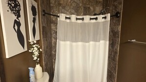 A bathroom with a shower curtain, toilet, sink, and a vase with flowers. - Big space on Deadwood`s Main Street! (Deadwood)