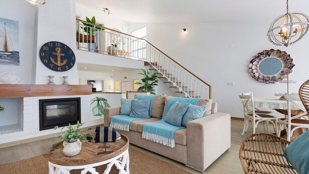 Una sala de estar moderna con chimenea, una escalera y un comedor.