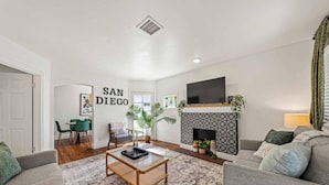 A living room with a fireplace, a sofa, a coffee table, and a TV.