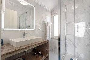 Een moderne badkamer met een marmeren wastafel, een douchecabine van glas en een grote spiegel.
