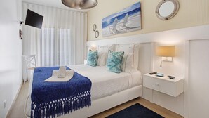 Une chambre à coucher avec un lit, une table de chevet, un téléviseur et un tableau au mur.