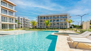 Um hotel moderno com piscina, espreguiçadeiras e um jardim ajardinado.