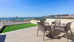 Een terras met uitzicht op de oceaan, met een tafel en stoelen.