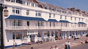 Een wit gebouw met een balkon en een bord met de tekst 'The Royal York & Faulkner Hotel'.