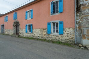 Ein Gebäude mit Steinwänden und blauen Fensterläden, einer Tür und einem Fenster.