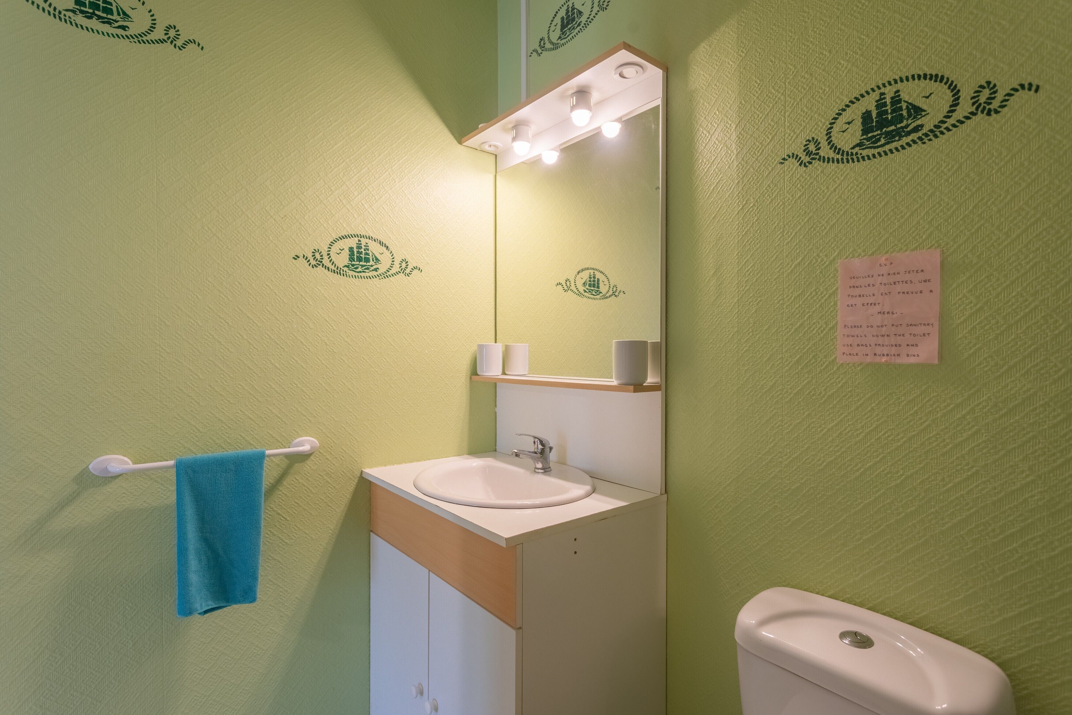 Een badkamer met een wastafel, spiegel, handdoekrek en toilet.