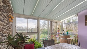Une terrasse couverte avec une table, des chaises et des plantes en pot.