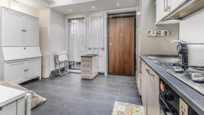 A modern kitchen with a built-in oven, a coffee machine, and a wooden door. - Battistini Sweet House (Roma)
