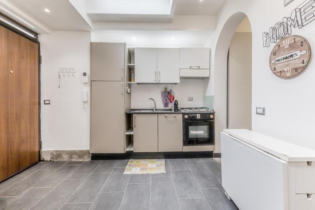 A modern kitchen with white cabinets, a built-in oven, and a small countertop.