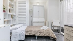 A bedroom with a bed, a wardrobe, a desk, and a window. - Battistini Sweet House (Roma)