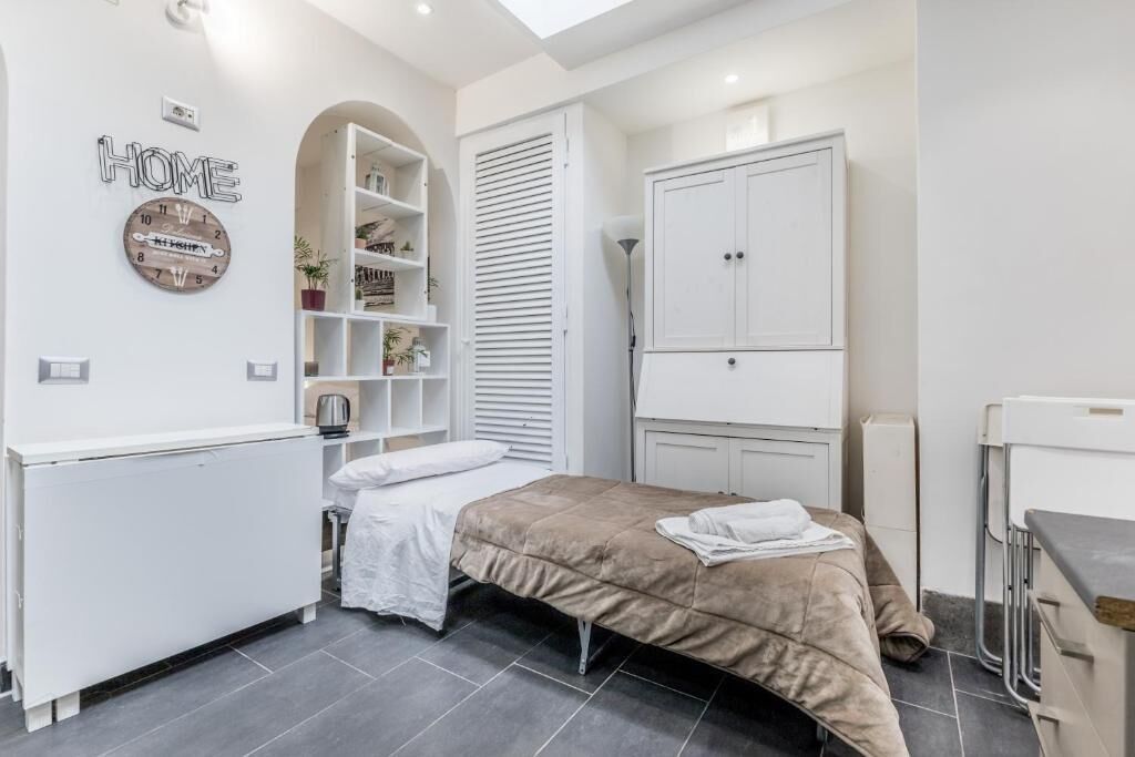 Ein Schlafzimmer mit einem Bett, einem Kleiderschrank, einer Regaleinheit und einer Uhr an der Wand.