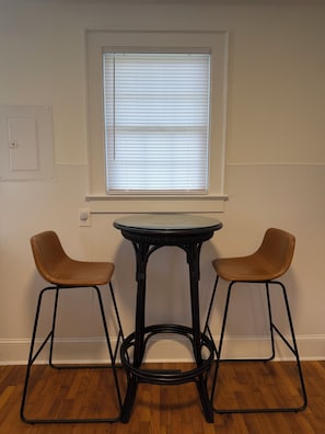 Een kamer met een raam, een tafel en twee stoelen.