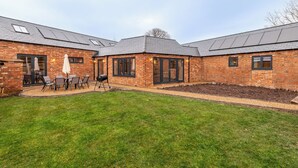 A brick building with a patio area, outdoor seating, and a covered section. - The Stables (Huntingdon)
