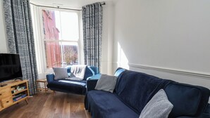 Ein Wohnzimmer mit einer Couch, einem Fernseher und einem Holzkabinett.