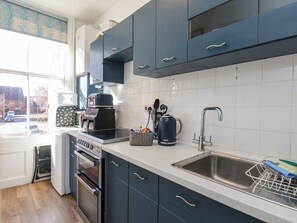 A modern kitchen with dark cabinets, a stainless steel sink, and a coffee maker. - Granby Place Apartment 2 (Scarborough)