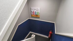 Portaikko, jonka seinä on maalattu siniseksi, siinä on palosammutin ja kyltti, jossa on kuvia värikkäistä rantataloista.