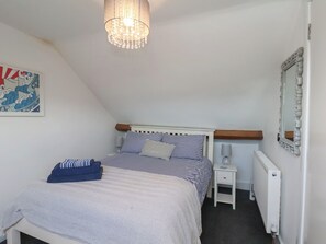 A bedroom with a bed, bedside tables, a radiator, a mirror, and a wall-mounted picture. - Granby Place Apartment 3 (Scarborough)