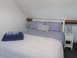 A bed with striped bedding, a pillow with 'Love' written on it, a blue towel, and a bedside lamp. - Granby Place Apartment 3 (Scarborough)