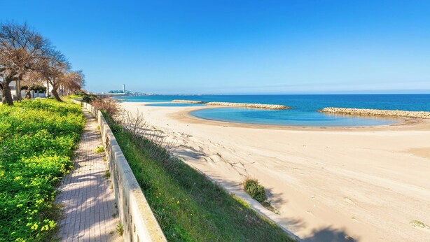 A beach with a paved walkway, a stone barrier, and a distant bridge. - Casa Blasi by BarbarHouse (San Pietro Vernotico)