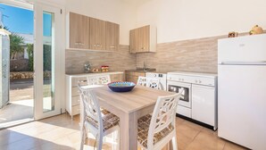 A modern kitchen with a dining area, featuring a large table, white chairs, and a built-in oven. - Casa Blasi by BarbarHouse (San Pietro Vernotico)