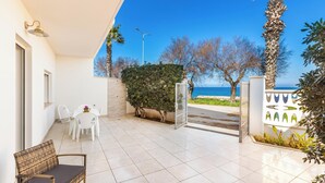 A balcony with a view of the sea, a white table with chairs, and a wicker chair. - Casa Blasi by BarbarHouse (San Pietro Vernotico)