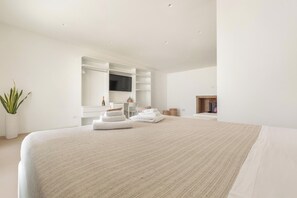 Een moderne slaapkamer met een groot bed, een flatscreen televisie, ingebouwde planken en een open haard.