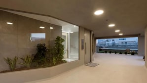 Een moderne hotelgang met een glazen wand, inbouwverlichting en uitzicht op het buiten.