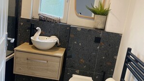 A bathroom with a white sink, a toilet, a mirror, and a shower area. - Modern 3 bed Home by Glasgow Airport (Paisley)