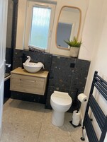 Un baño con lavamanos blanco, inodoro, espejo y zona de ducha.