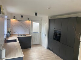 Una cocina moderna con salpicadero de mármol, estufa empotrada y muebles oscuros.