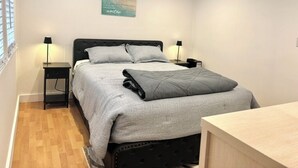 Ett sovrum med en säng, sängbord, ett skrivbord och ett konstverk som hänger på väggen.