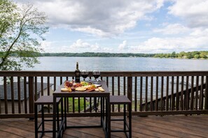 A wooden deck with a table set for a meal, overlooking a lake. - The Grand Legacy Lodge  (Big Lake)