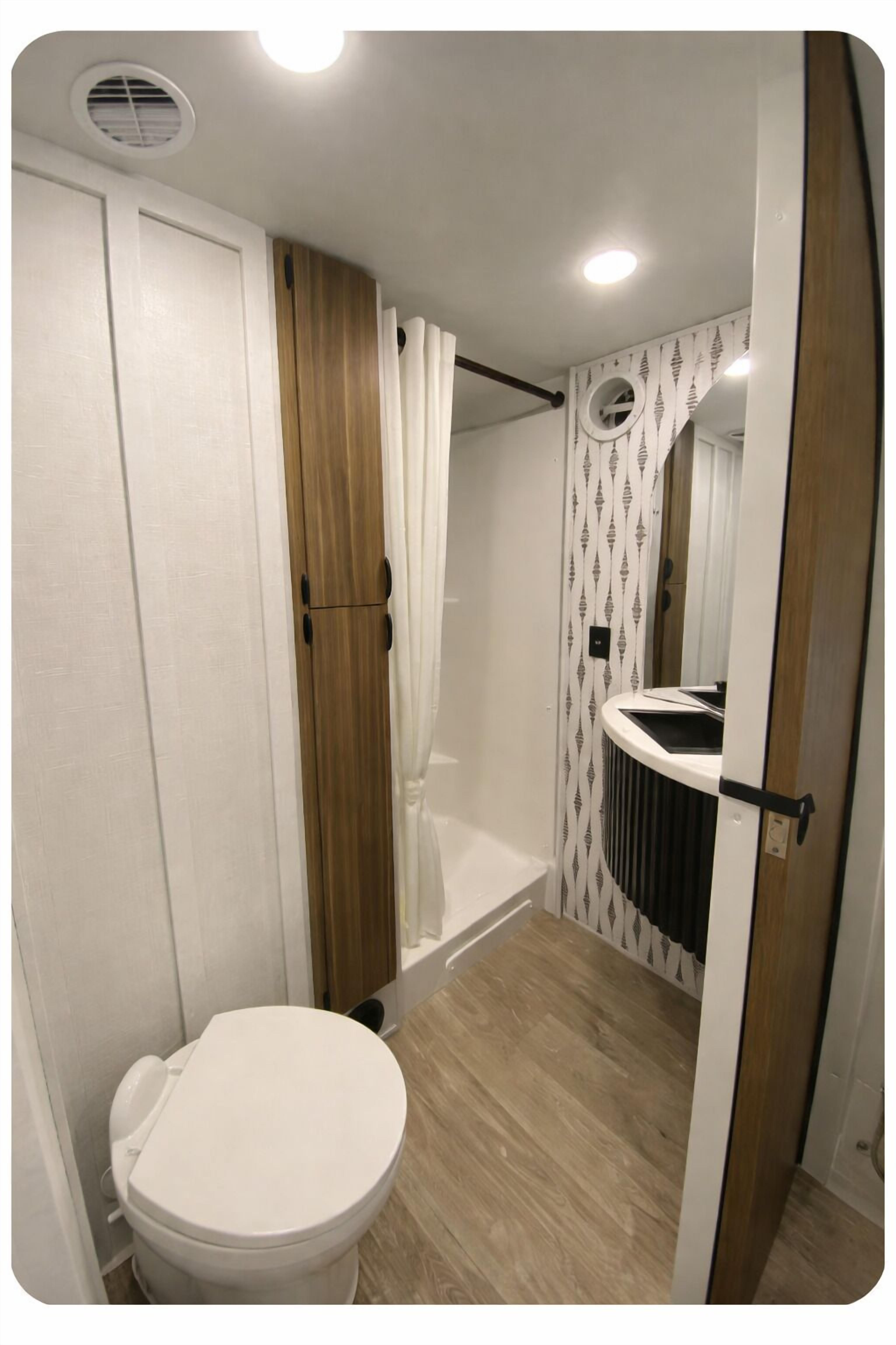 A bathroom with a toilet, shower, and sink.