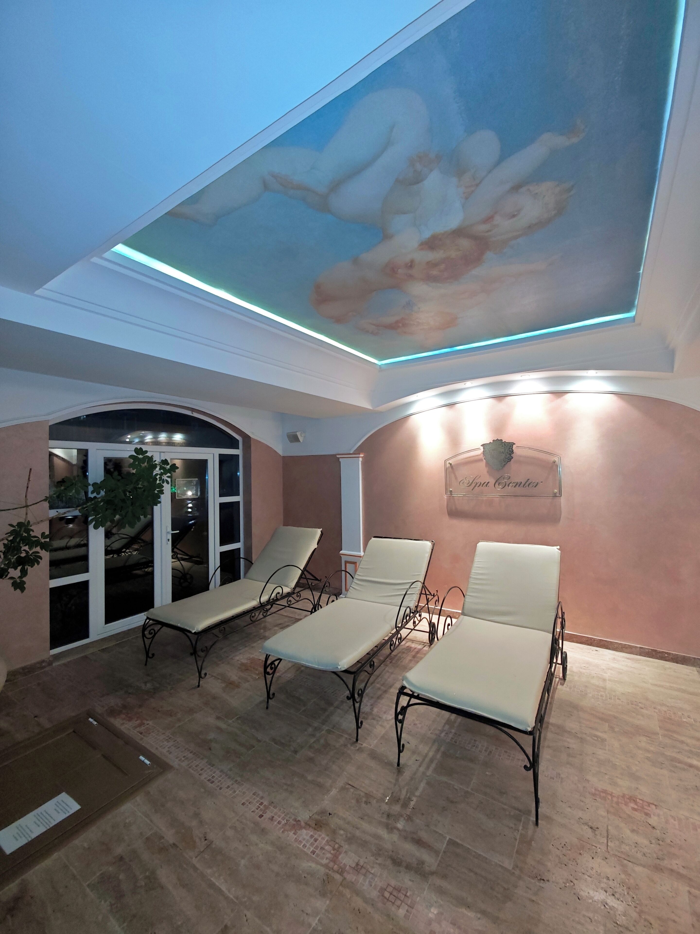 A spa center with a ceiling mural, lounge chairs, and a sign indicating the spa center.