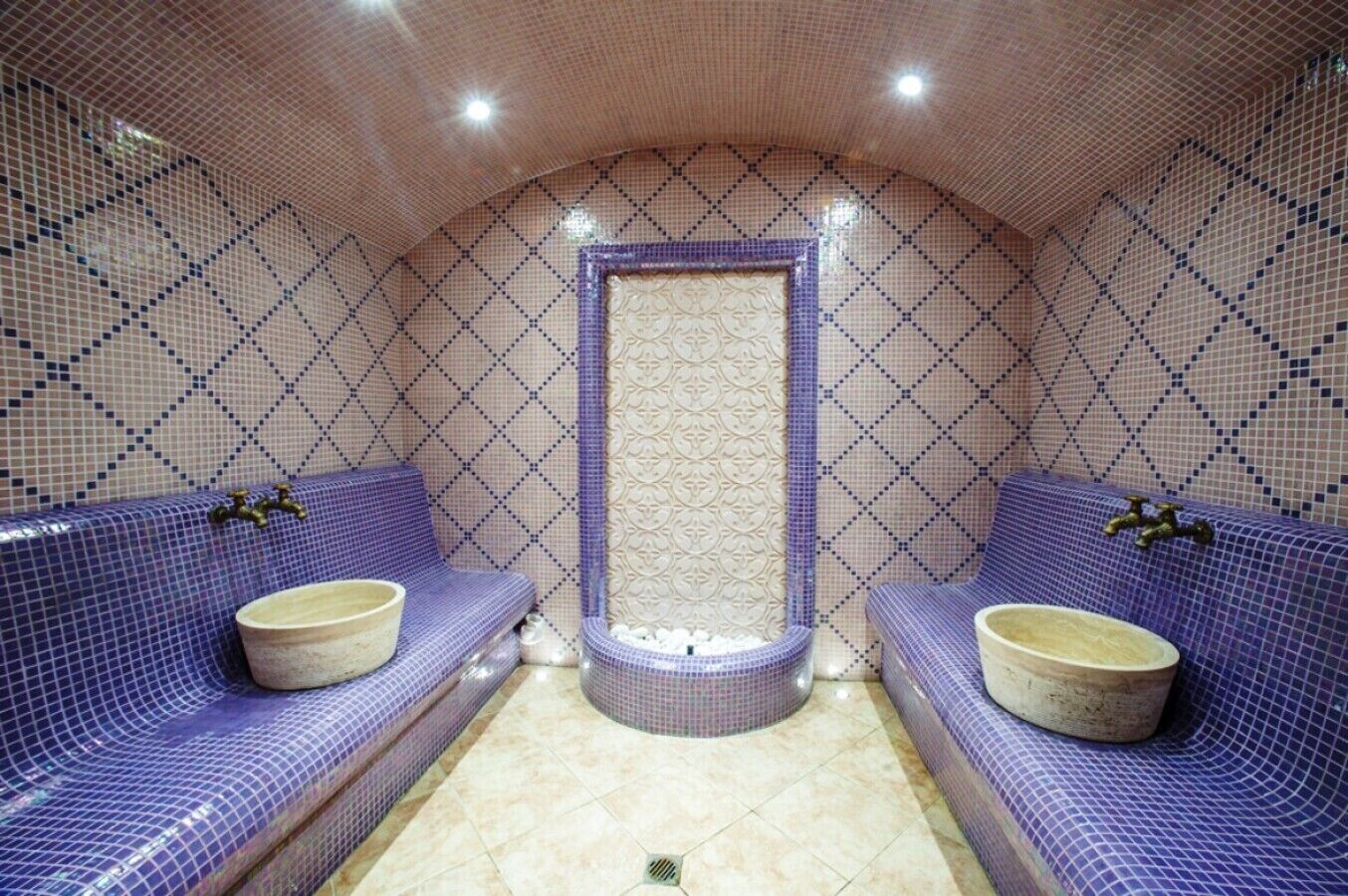 A bathroom with two sinks, a bathtub, and a shower area, all with patterned tile walls and floor.