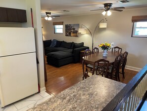 A compact living space with a dining area, a sofa, a ceiling fan, and a window.