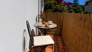 A small outdoor patio with a round table, two chairs, a white bench, and a bamboo fence. - Nonna Lucia apartment: comfort and relaxation in Lotzorai (Lotzorai)