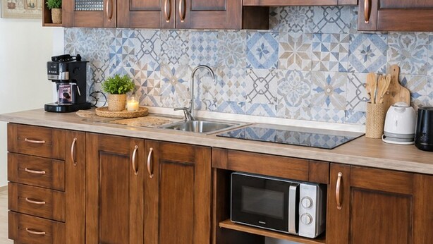 A kitchen with wooden cabinets, a built-in microwave, and a tiled backsplash. - Nonna Lucia apartment: comfort and relaxation in Lotzorai (Lotzorai)