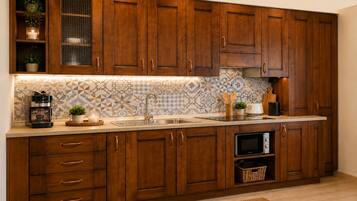 Una cucina con mobili in legno, forno integrato, macchina da caffè e zoccolo a mosaico.