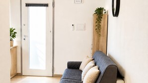 A modern living room with a sofa, a door, a wall-mounted plant, and a light switch. - Nonna Lucia apartment: comfort and relaxation in Lotzorai (Lotzorai)