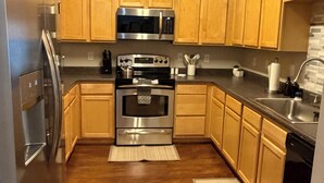A kitchen with wooden cabinets, stainless steel appliances, and a black countertop. - Cozy and Inviting  2-bedroom apartment minutes away from downtown. (Boone)