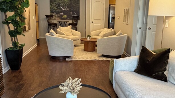 A living room with a sofa, two armchairs, a coffee table, a plant, and a painting on the wall. - Cozy and Inviting  2-bedroom apartment minutes away from downtown. (Boone)