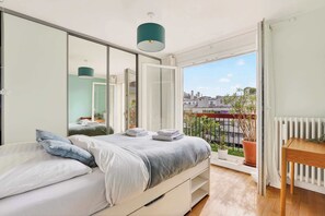 Une chambre à coucher avec un lit, une table de chevet, une fenêtre donnant sur un paysage agréable et un radiateur.