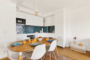 A modern kitchen with white cabinets, a microwave, and a blue-tiled backsplash. - Bright & Quiet 3BR with Balconies in Paris 11th (Paris)